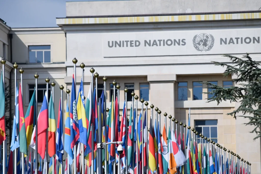 Fargerike flagg utenfor FNs kontor i Genève som symboliserer global enhet.